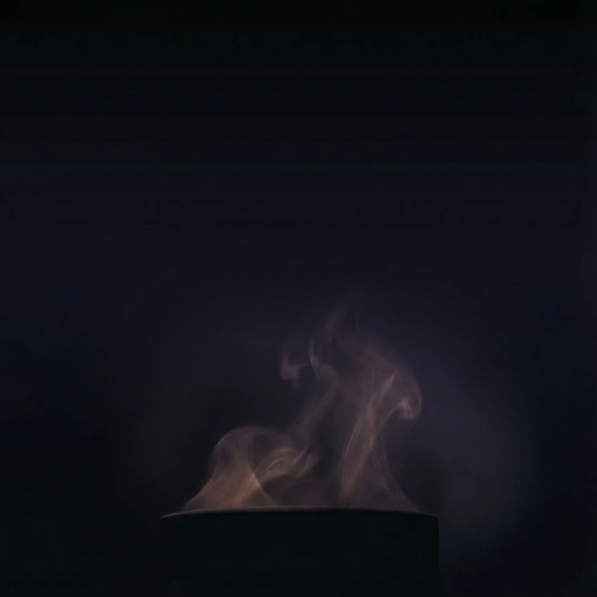 Atmospheric smoke rising from tea in the darkness