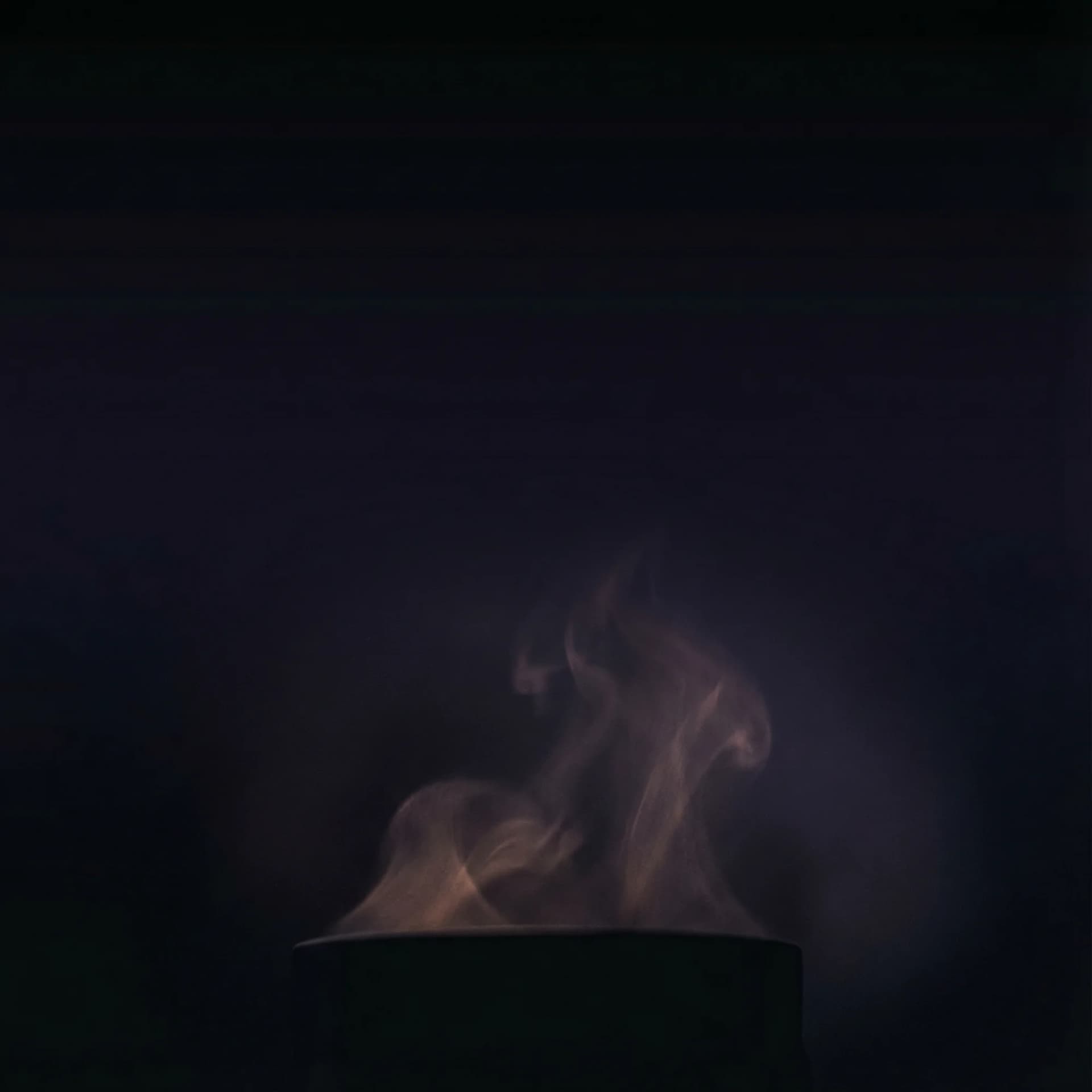 Atmospheric smoke rising from tea in the darkness